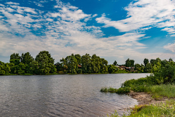 Landscape, beautiful summer. A village on the Bank of a wide river, beautiful, Cumulus clouds on a blue sky on a summer day.