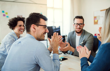 Group of young businesspeople sitting around table in a modern office, having meeting.