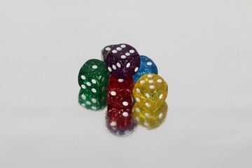 heap of sparkling colorful dices on a silver ground with mirror effect
