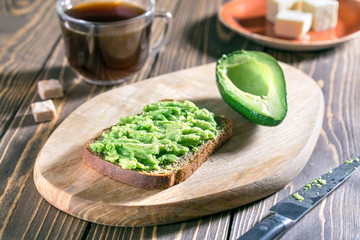 Healthy toasts with avocado and cup of black coffee on wooden table. Healthy food for breakfast.