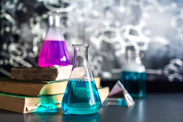 Glass in a chemical laboratory filled with colored liquid during a reaction against the background...