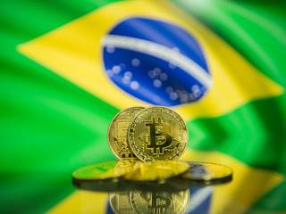 Bitcoin gold coin and defocused flag of Brazil background. Virtual cryptocurrency concept.