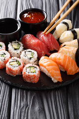 Japanese sushi food served on blackboard plate. Sushi roll with prawn, avocado, salmon, tuna, sesame close-up. Vertical