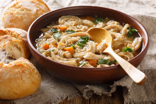 Close-up of stewed flaczki with vegetables in a bowl served with bread. horizontal