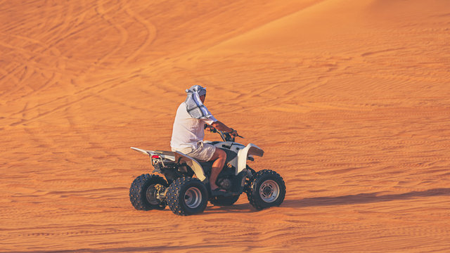 One Man On Quad Bike ATV Exploring Desert Alone With Head Covered By Keffiyeh. Adventure Concept With Tourist Discover Earth On Quad Biking Dubai Tour – Dune Bashing And Dune Buggy Activities