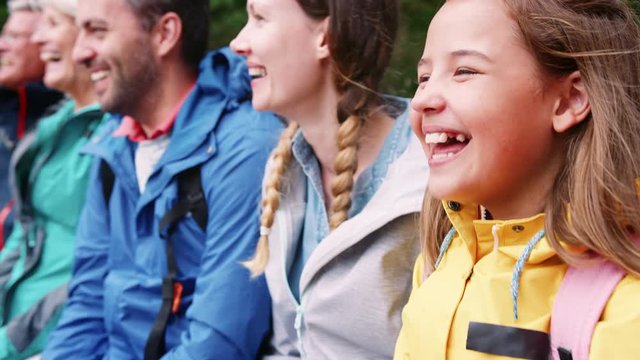 Camera moving in slow motion along multi generation family sitting in a row laughing, head and shoulders, close up, Lake District, UK