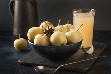 Pickled apples in bowl and apple sidr on dark stone table. - obrazy, fototapety, plakaty