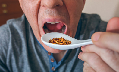 Closeup of unrecognizable man eating a spoonful of worms