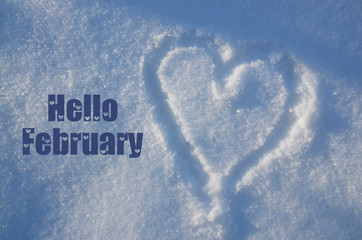 Hello February greeting card with heart drawing on natural white snow on a sunny day.Winter season...