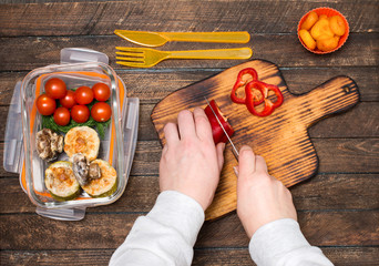 Woman preparing takeaway meal for children or her husband. School lunch box with salad, stuffed vegetable marrow, baked mushrooms and dried apricots. Healthy eating habits concept.