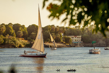 Scenic egyptian sunset on the Nile river with Felluca boats in Luxor Egypt - obrazy, fototapety, plakaty