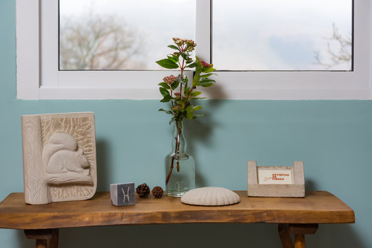 table with stone sculptures under a window and turquoise background