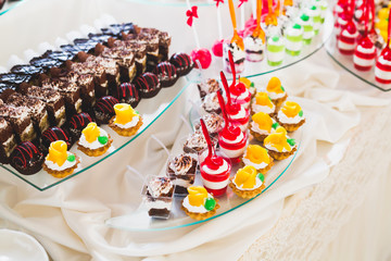 Delicious and tasty dessert table with cupcakes shots at reception closeup