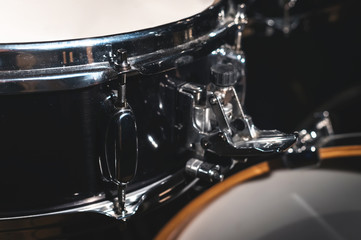 Obraz na płótnie Canvas Closeup view of a drum set in a dark studio. Black drum barrels with chrome trim. The concept of live performances