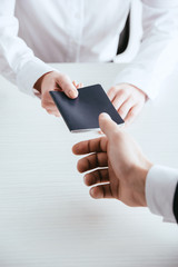 cropped view of female travel agent giving passport to tourist