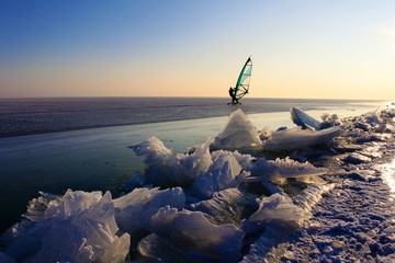 eissurfen auf zugefrorenem see im winter/sport am eis, abendliche stimmung am neusiedlersee in österreich/segel, himmel, schnee, alleine im schnee, blick auf die weite des horizonts