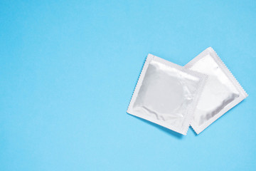 Condoms package on light blue background with copy space. A condom use to reduce the probability of pregnancy or sexually transmitted disease (STD). Safe sex and reproductive health concept.