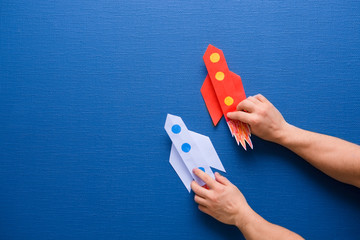 male hands hold a rocket from paper on a blue background