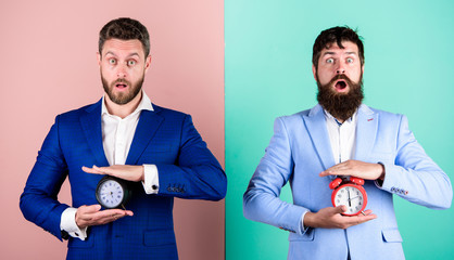 Men business formal suits hold alarm clocks. Lack of self discipline in time management leads...