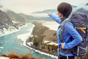 Fototapeta premium Hiking smiling woman with a backpack in mountains. Beautiful young girl is traveling in the mountains.