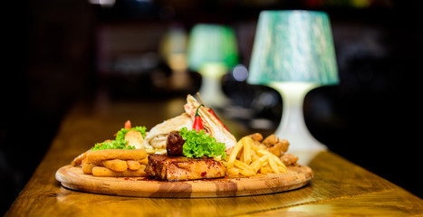 Pub menu snack. High calorie snack for group friends. Tasty delicious snacks. Snack for beer. Restaurant food. Wooden board with lot french fries fish sticks burrito and meat steak served with salad