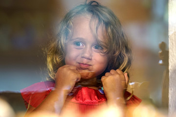 Beautiful little girl looks in the window of a shop in OIA, and makes funny faces
