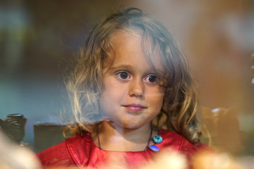 Beautiful little girl looks in the window of a shop in OIA, and makes funny faces