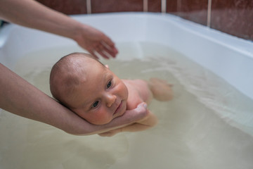 Children's therapy in warm water. Bathing baby in the bathroom