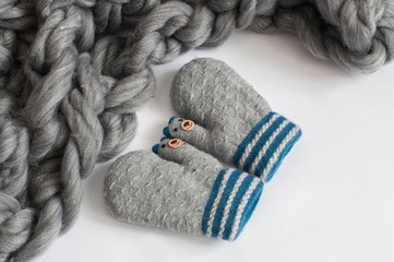 Fototapeta na wymiar Pair of grey knitted mittens on a white background