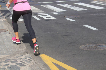 Woman in pink shirt and trainers running in the city