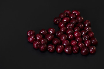 heart made of red cherries on a black background