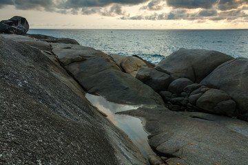 a backwater on the rocks of the Kata beach of the Phuket island of Thailand at evening