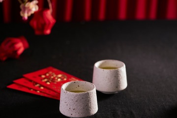 Lunar new year food and drink still life on black background. Translation of text paper in image: Prosperity