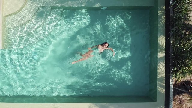 A young glamorous woman in a bikini in a pool in a luxury villa