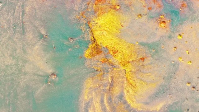Colorful sparkling paints mix in beautiful patterns. Oil ink of yellow, turqoise and other colors spread on the surface and mix one into another creating amazing textures and design.