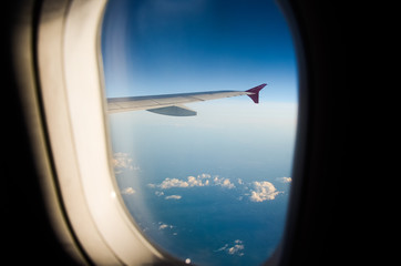 Naklejka na ściany i meble Airplane flying above clouds at sunrise. Aerial window view