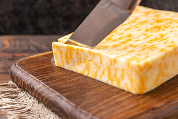 Marble cheese on dark wooden background.