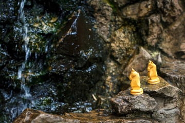 two wooden chess knights at a watterfall