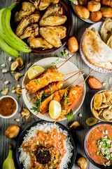 West african food concept. Traditional Wset African dishes assortment - peanut soup, jollof rice, grilled chicken wings, dry fried bananas plantains, nigerian chicken kebabs, meat pies, top view