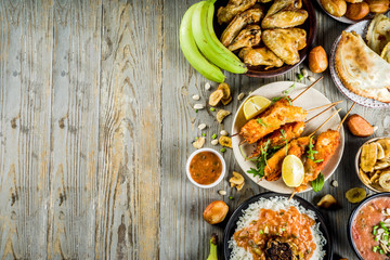 West african food concept. Traditional Wset African dishes assortment - peanut soup, jollof rice, grilled chicken wings, dry fried bananas plantains, nigerian chicken kebabs, meat pies, top view