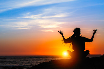 Fototapeta na wymiar Yoga meditation woman on the ocean during amazing sunset.
