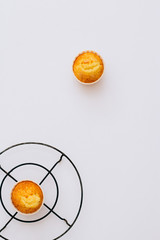 Flat lay minimalism homemade orange muffins on a metal stand under the hot on a white background, top view, copy space