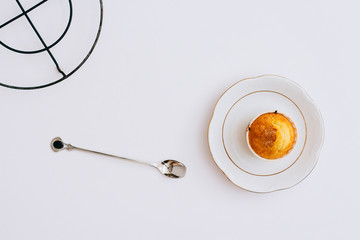 Flat lay minimalism homemade orange muffins on a metal stand and plate under the hot on a white background, top view, copy space