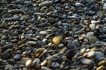 pebble stones on the sea beach, the rolling waves of the sea with foam