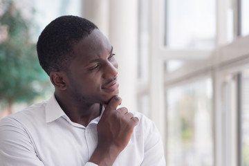 Thoughtful African man thinking; portrait of pensive young adult african man thinking or planning;...