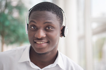 Modern African man listening to music headsets; portrait of happy smiling Black African man...