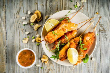 West african food, spicy nigerian chicken kebabs with peppered sauce, chin chin and dry plantains, wooden background copy space top view