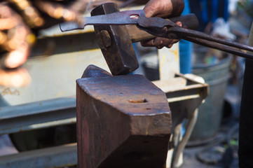 blacksmith performs the forging of hot glowing metal on the anvil