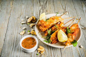West african food, spicy nigerian chicken kebabs with peppered sauce, chin chin and dry plantains, wooden background copy space top view