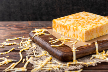 Marble cheese on dark wooden background.